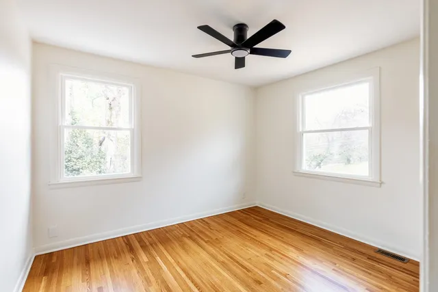 a view of empty room with wooden floor and window