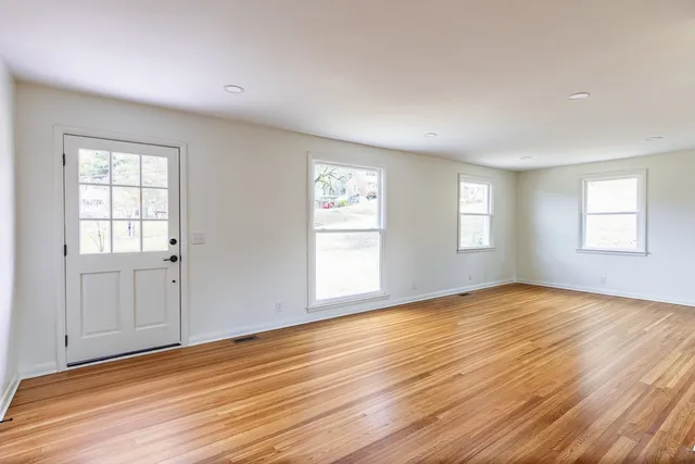 an empty room with wooden floor and windows