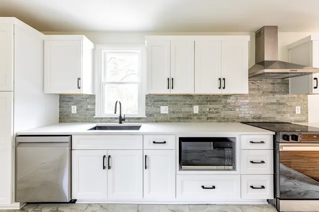 a kitchen with granite countertop white cabinets and white appliances