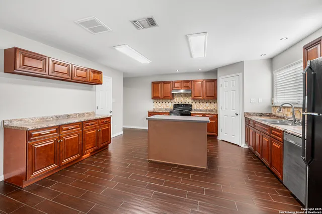 a kitchen with stainless steel appliances granite countertop a stove a sink dishwasher and a refrigerator