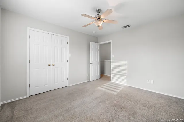a view of an empty room with chandelier fan