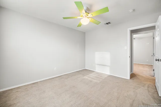 an empty room with a chandelier fan and a window