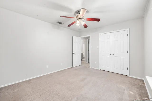 an empty room with chandelier fan