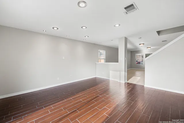 an empty room with wooden floor and windows