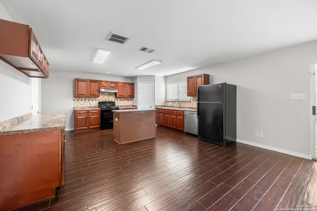 a living room with stainless steel appliances kitchen island granite countertop wooden floor and a view of kitchen