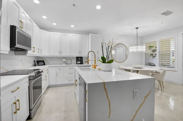 a kitchen with white cabinets and clock