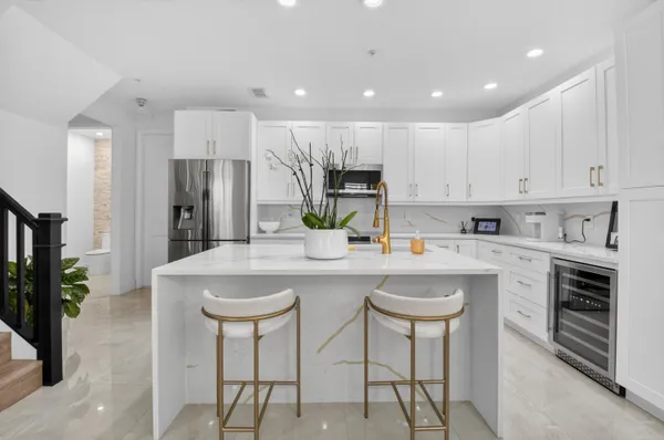 a kitchen with granite countertop a sink dishwasher stove and white cabinets with wooden floor