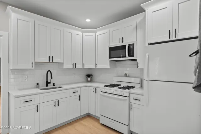 a kitchen with granite countertop white cabinets sink and stainless steel appliances