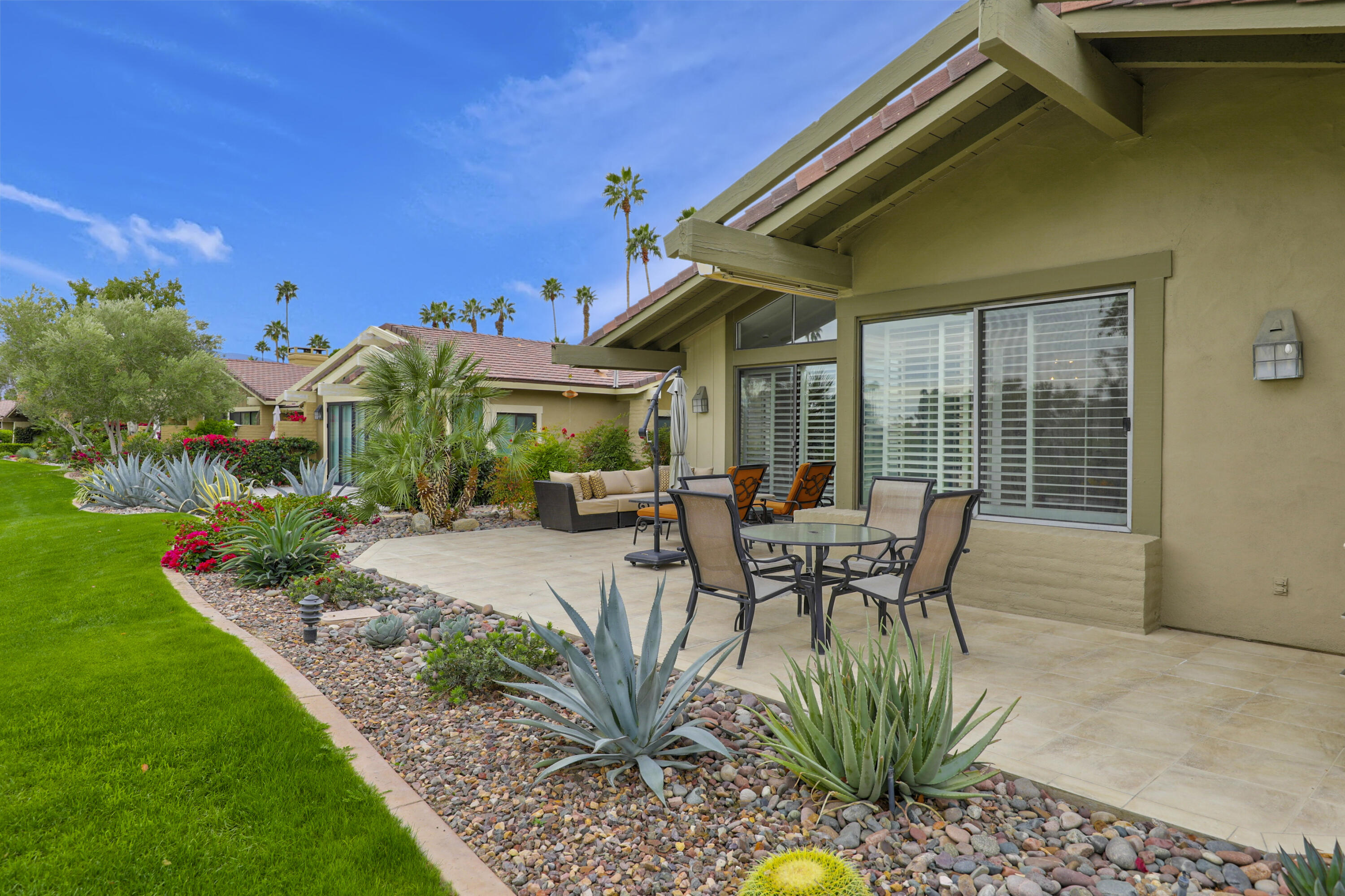 148 Deer Spring Way Palm Desert, CA 92211 - Photo 25 of 54 a view of a patio with table and chairs with plants and trees