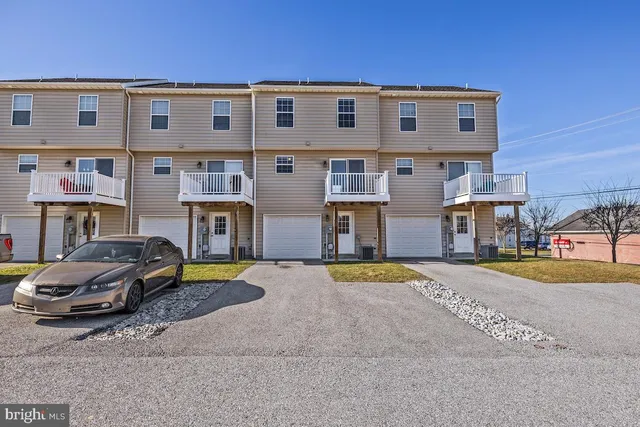 a front view of a house with a yard and a car parked