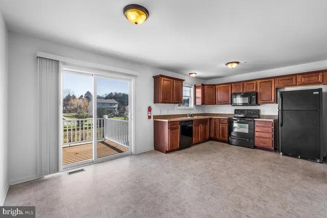 a kitchen with stainless steel appliances a refrigerator a sink a stove top oven and a view of living room