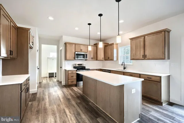 a kitchen with stainless steel appliances kitchen island granite countertop a stove a sink and a refrigerator