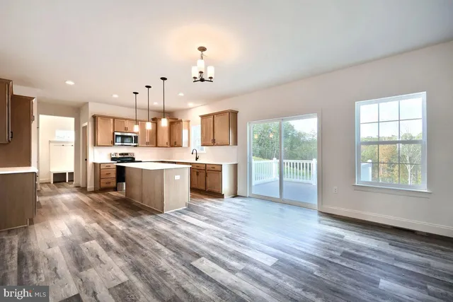 a large kitchen with stainless steel appliances kitchen island a large counter top and a wooden floors