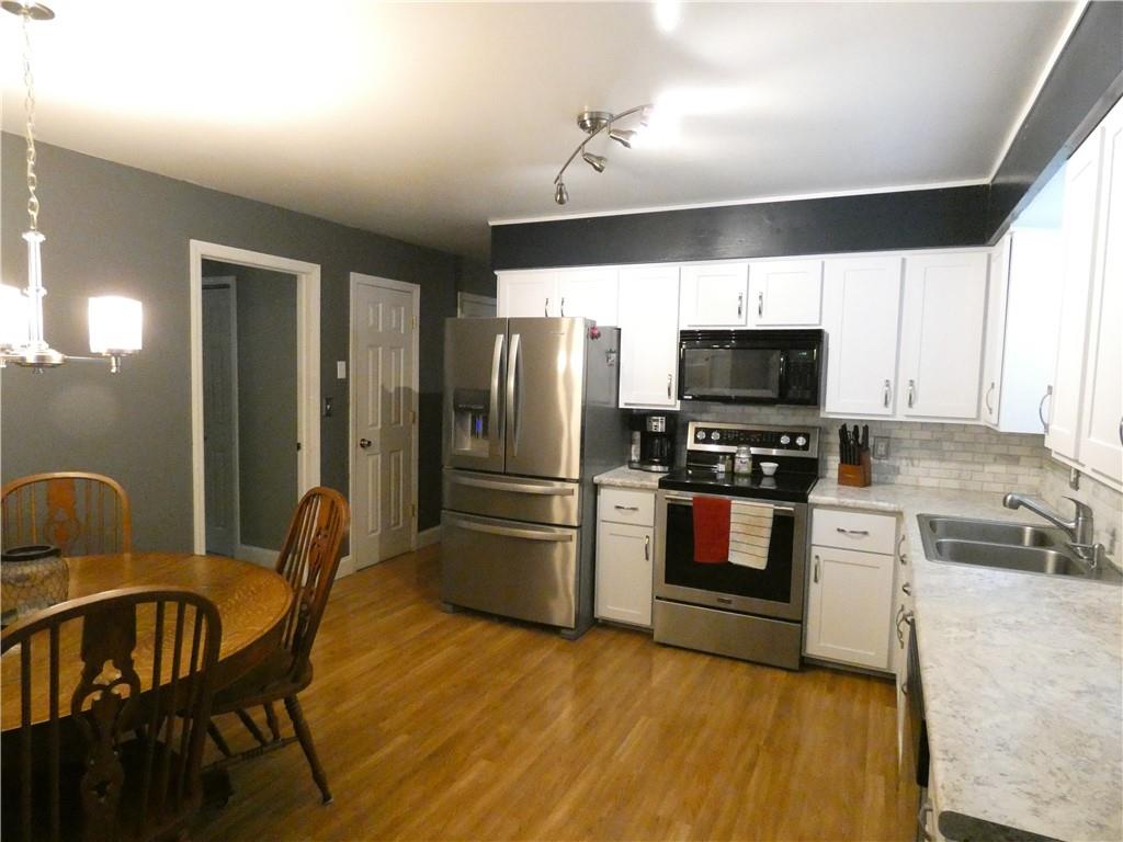 447 Pfeifer Road Prospect, PA 16052 - Photo 5 of 14 a kitchen with stainless steel appliances kitchen island granite countertop a refrigerator a stove a microwave oven with white cabinets and wooden floor