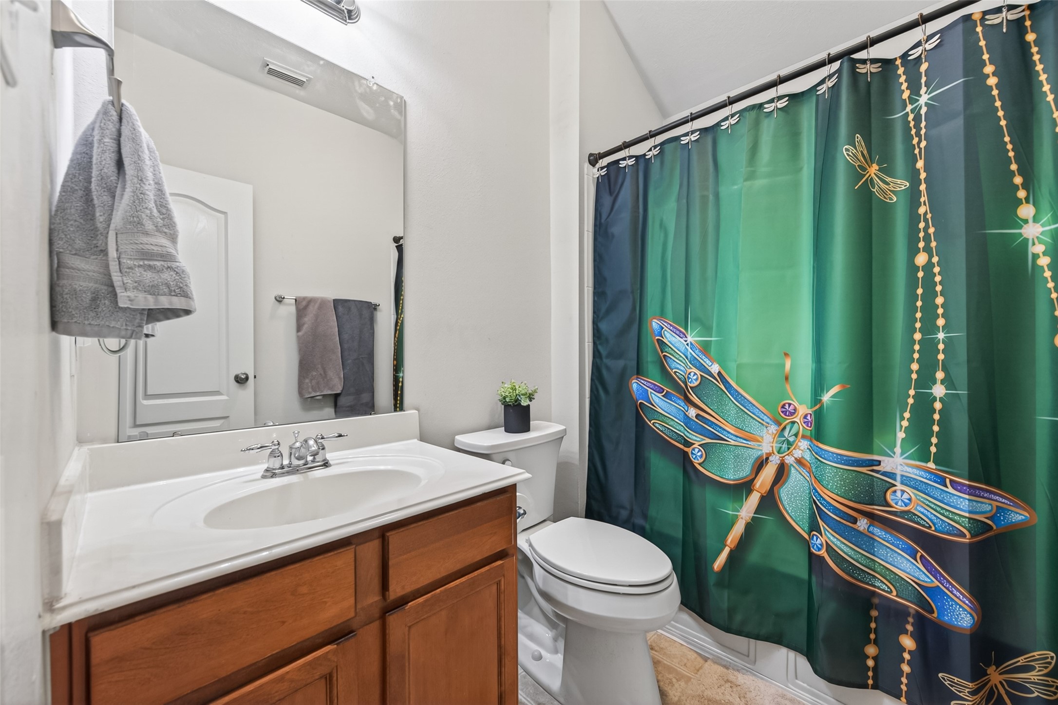 8622 Henrico Lane Rosenberg, TX 77469 - Photo 16 of 20 This bathroom features a clean, modern design with a granite-topped vanity, ample cabinetry, and a striking dragonfly-themed shower curtain that adds a touch of whimsy.