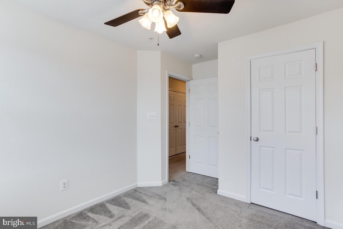 102 Backstretch Way Prince Frederick, MD 20678 - Photo 32 of 44 an empty room with a chandelier fan and kitchen view