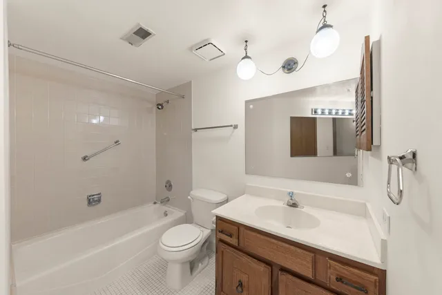 a bathroom with a toilet a sink a mirror a bathtub and vanity