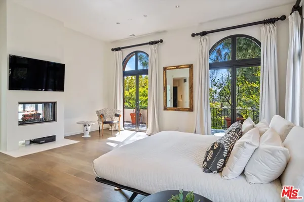 a bedroom with a bed a mirror and a large window