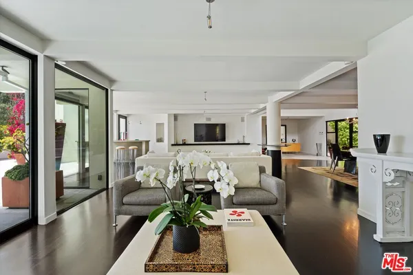 a living room with furniture floor to ceiling window and a flat screen tv