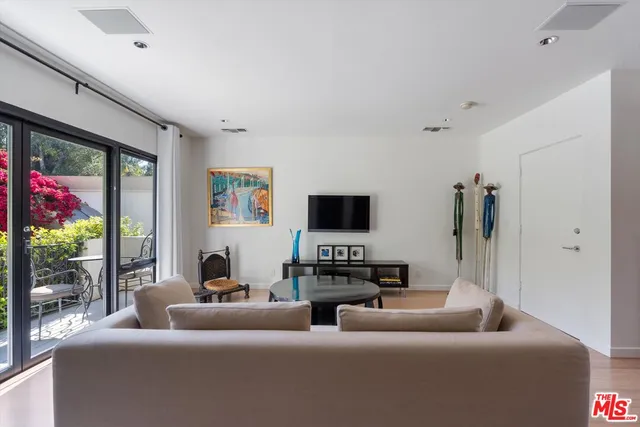 a living room with furniture a flat screen tv and a floor to ceiling window