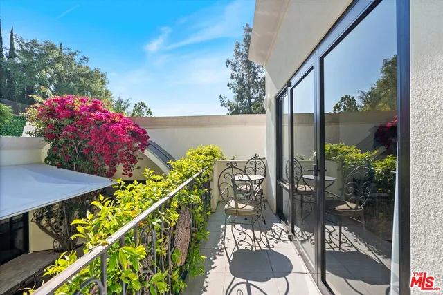 a view of a balcony with chairs potted plants