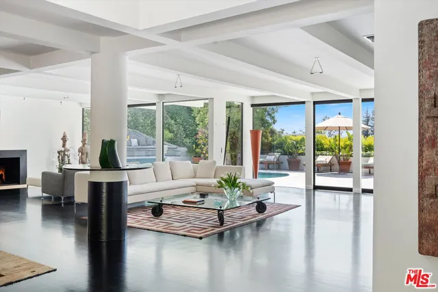 a living room with furniture large windows and wooden floor