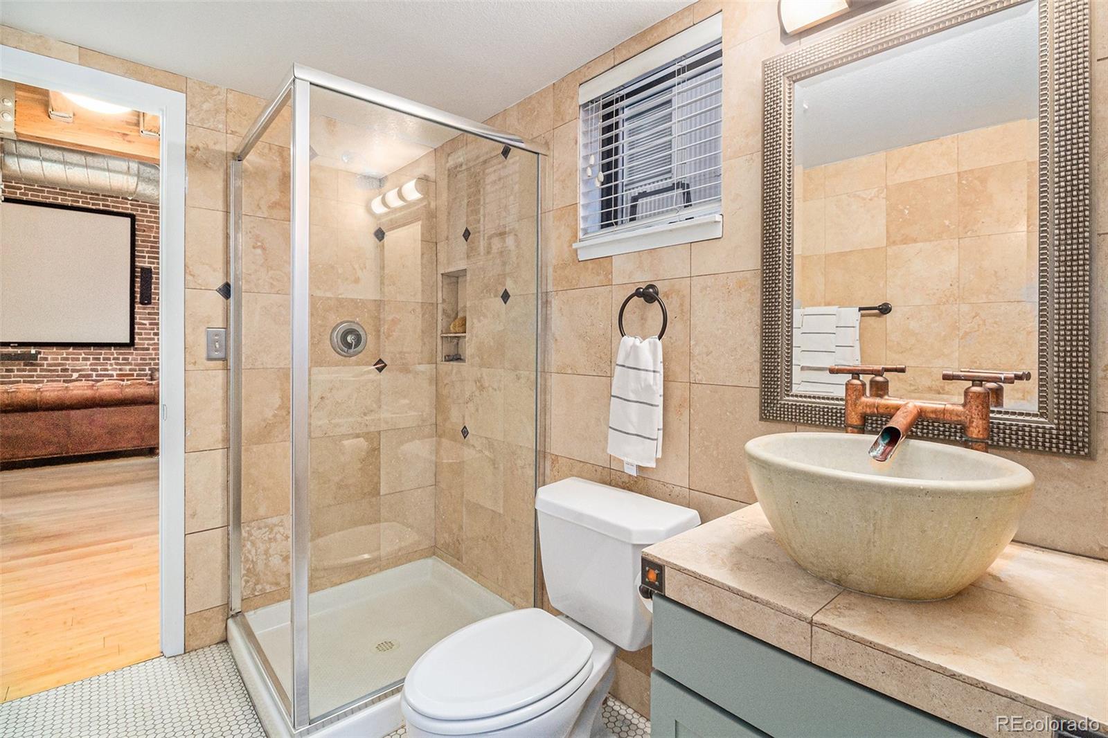 3225 Blake Street, Unit 24 Denver, CO 80205 - Photo 15 of 25 a bathroom with a sink a toilet a mirror and a glass door shower