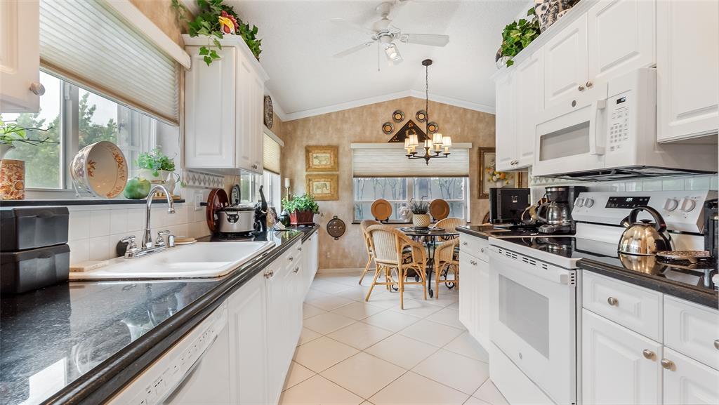 7844 Travelers Tree Drive Boca Raton, FL 33433 - Photo 11 of 40 a kitchen with stainless steel appliances granite countertop a sink dishwasher a stove a dining table and chairs with wooden floor