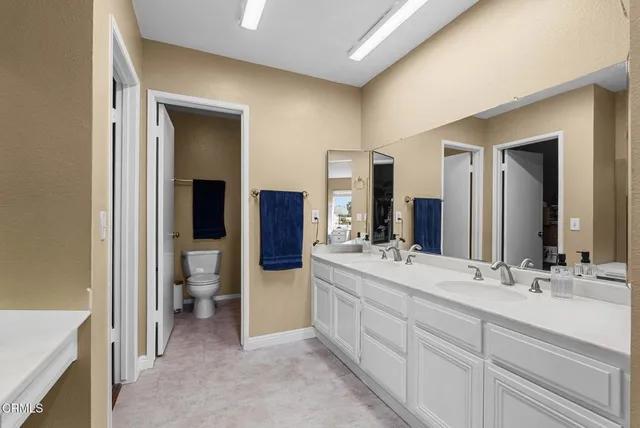 a bathroom with a double vanity sink mirror and toilet