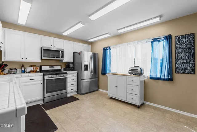a kitchen with granite countertop white cabinets and stainless steel appliances