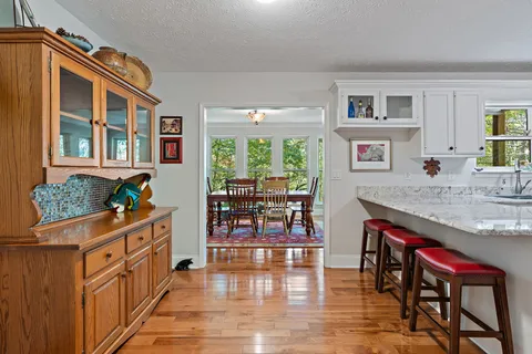 a kitchen with stainless steel appliances granite countertop a stove top oven a sink a dining table and chairs