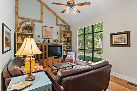 a living room with furniture a flat screen tv and a floor to ceiling window