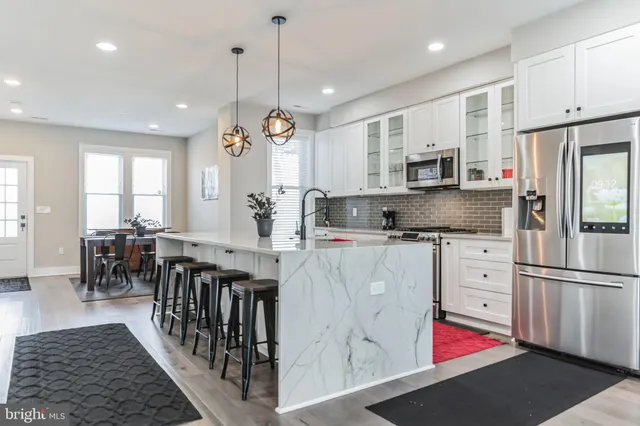 a kitchen with stainless steel appliances granite countertop a refrigerator a sink dishwasher a oven and a dining table with wooden floor