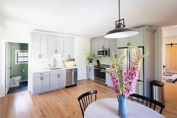 a kitchen with stainless steel appliances kitchen island granite countertop a refrigerator a stove a sink dishwasher and white cabinets with wooden floor