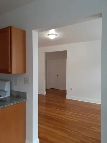 a view of an empty room with wooden floor and a cabinet