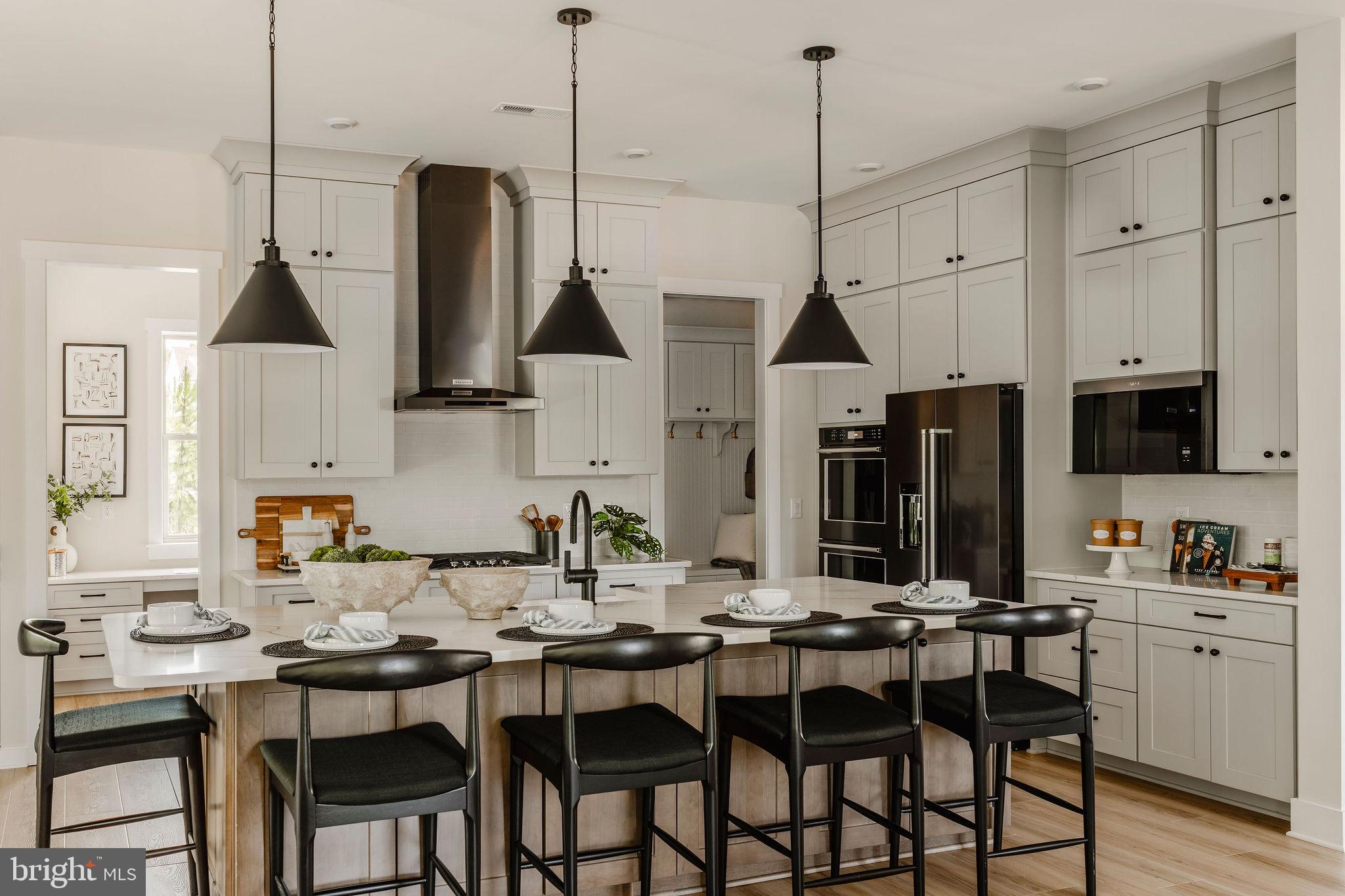 707007728 Hook Road, Unit COVINGTON Westminster, MD 21157 - Photo 12 of 48 a kitchen with stainless steel appliances kitchen island granite countertop a table chairs in it and white cabinets