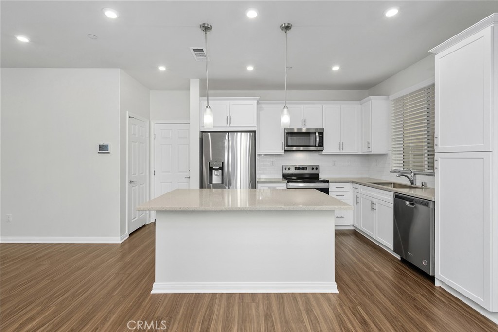 913 Helena Ridge Lake Elsinore, CA 92530 - Photo 13 of 38 a kitchen with stainless steel appliances granite countertop a refrigerator a stove top oven a sink and dishwasher with wooden floor