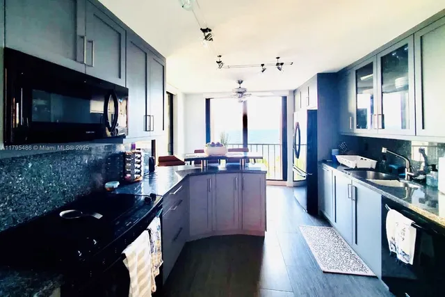 a kitchen with stainless steel appliances granite countertop a stove a sink dishwasher a microwave oven and a refrigerator with wooden floor