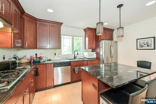 a kitchen with stainless steel appliances granite countertop a sink a stove and a wooden cabinets