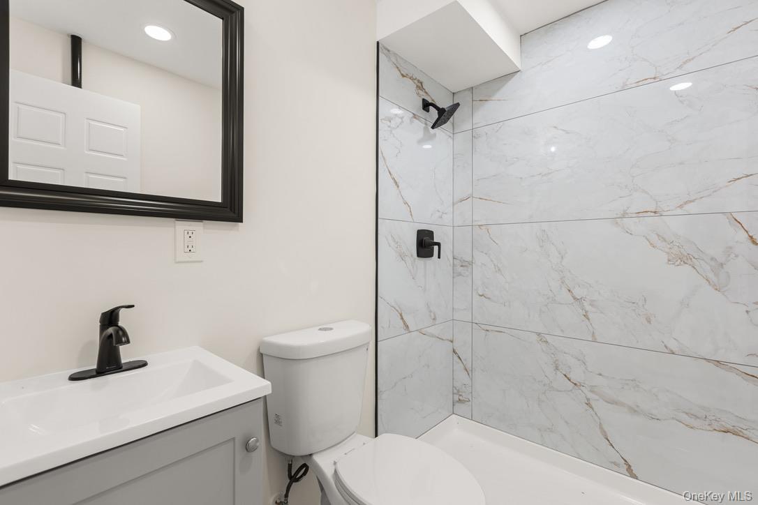 31 Grove Street Hempstead, NY 11550 - Photo 14 of 17 a bathroom with a toilet a sink and mirror