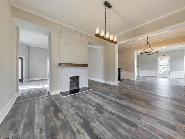 a view of a livingroom with a chandelier fireplace and wooden floor