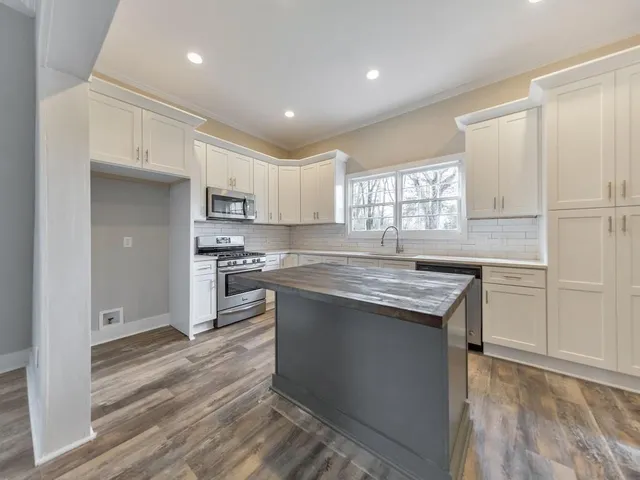 a kitchen with kitchen island granite countertop a sink cabinets and stainless steel appliances