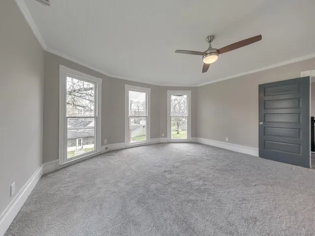 a view of an empty room with a window and a kitchen