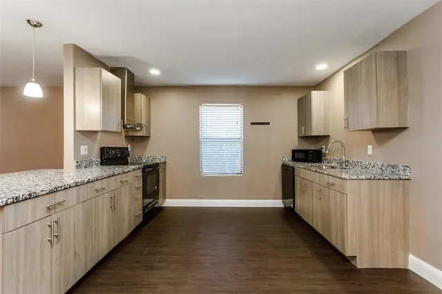 a kitchen with stainless steel appliances granite countertop a sink a stove and a wooden floors