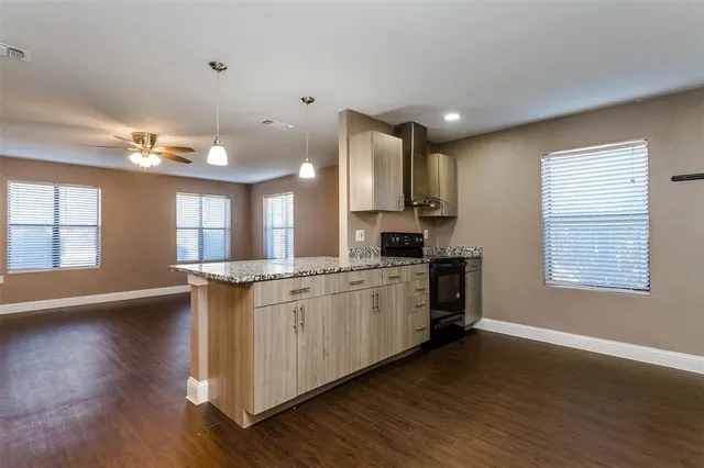 a view of a kitchen with a kitchen island wooden floor stainless steel appliances and a window
