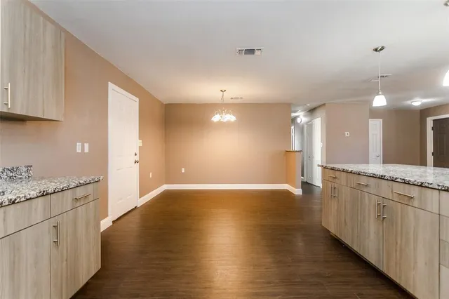 a kitchen with stainless steel appliances granite countertop a stove a sink and white cabinets with wooden floor