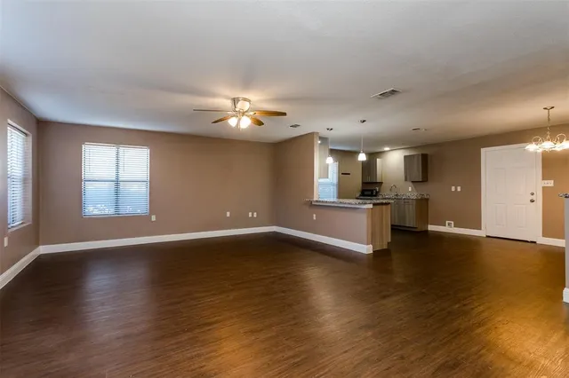 a view of an empty room with window and wooden floor