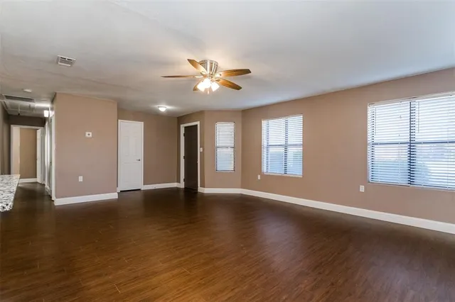 a view of an empty room with window and wooden floor