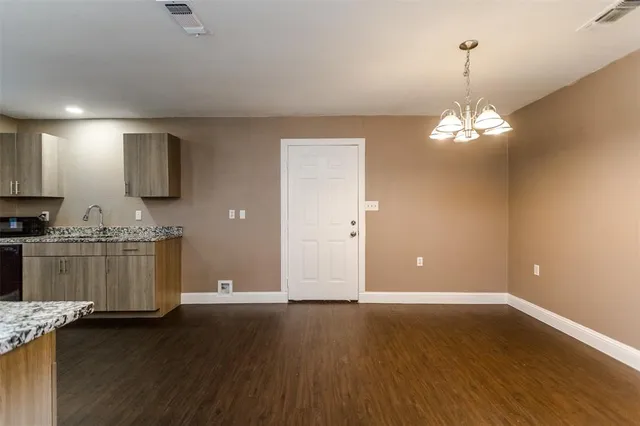 a view of a kitchen with granite countertop wooden floor and stainless steel appliances