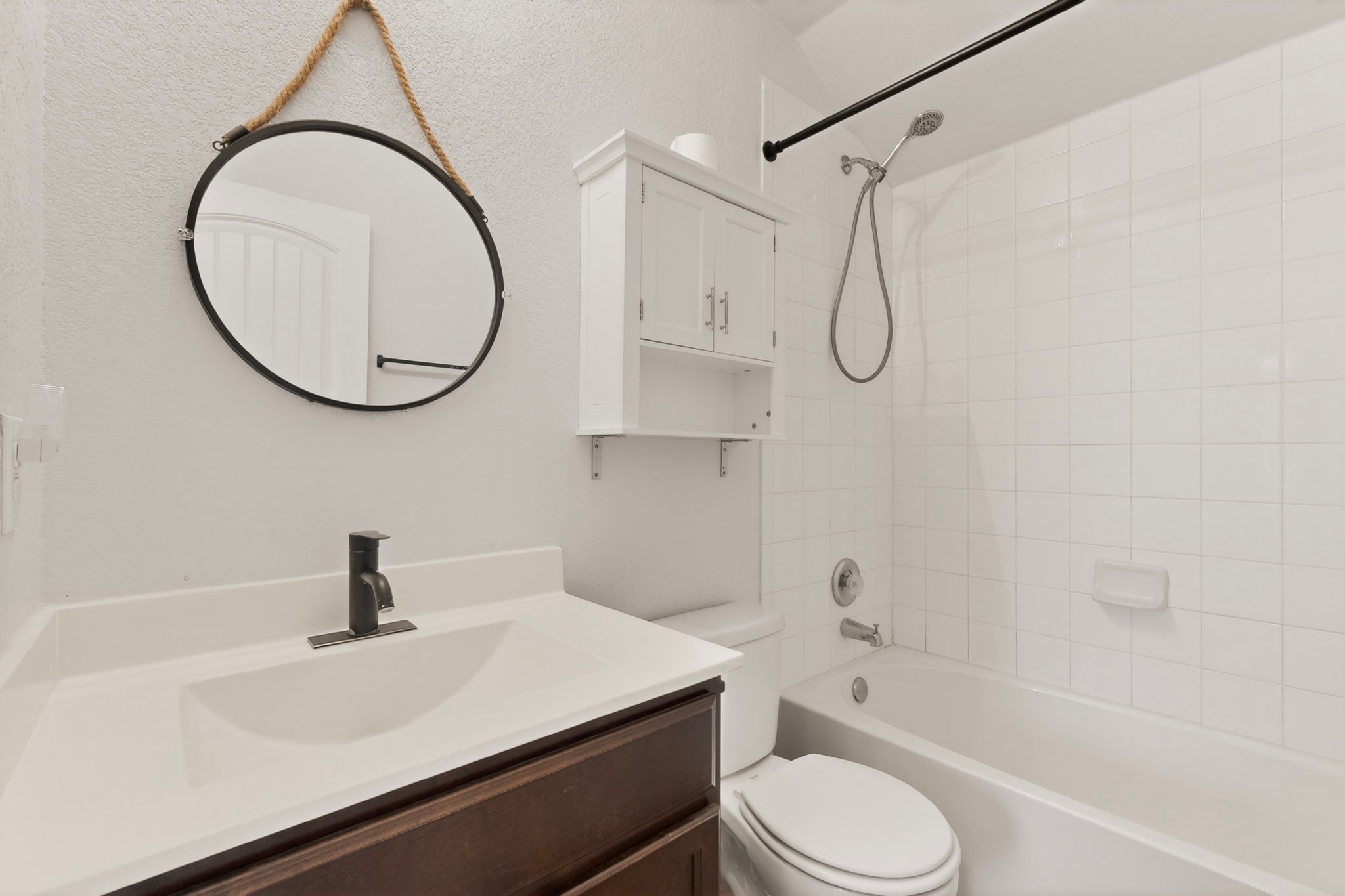 5905 Diamondleaf Bend Austin, TX 78724 - Photo 29 of 38 Bathroom featuring a modern vanity with a white countertop, dark wood-finish cabinetry, and a circular mirror with rope detail